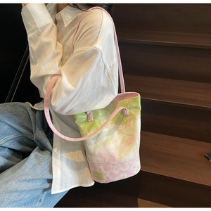 Detail of floral bucket bag with MOOG label worn by model on wooden stairs