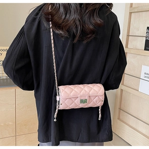 Rear view of a pink quilted cylinder crossbody bag with chain strap worn by a model