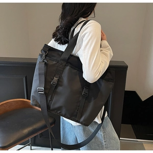 Detail of a black nylon tote bag with adjustable side buckles and durable carry straps