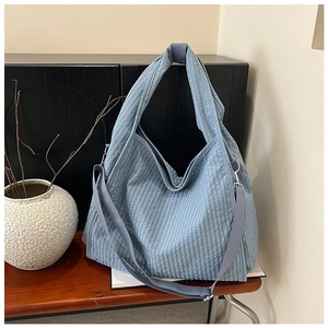 Detail of light blue textured canvas tote showing bubbly seersucker fabric and strap