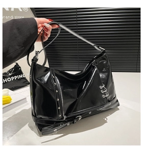 Detail view of black patent leather tote bag with punk silver rings and studs