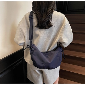 Detail of dark grey nylon dumpling bag with adjustable strap on a model back view