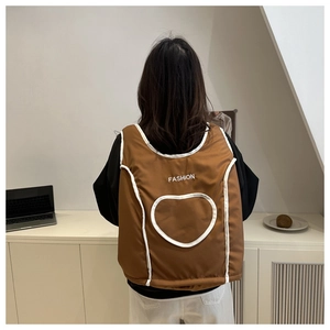 Detail of a brown quilted vest featuring a white heart pattern and FASHION text design