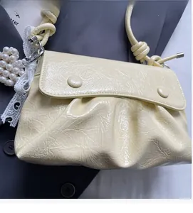 Détail du sac plissé crème en cuir avec breloque perle et bandoulière à nœud