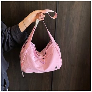 Detail view of pink nylon crossbody bag with wide shoulder strap and spacious side pocket