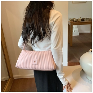 Pink pleated pillow bag worn as an underarm style with minimalist design detail