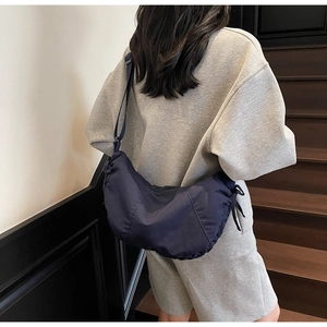 Detail view of navy blue nylon tote bag with drawstring on a model in a casual setting