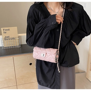 Close-up of pink quilted cylindrical chain bag with silver twist lock and leather strap