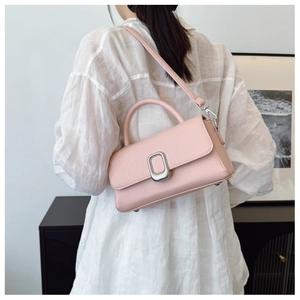 Pink lychee grain leather crossbody bag with silver buckle worn on white linen shirt