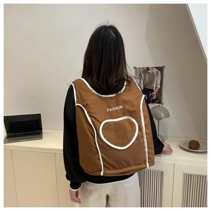 Detail of caramel brown vest-style backpack with white heart and fashion logo print
