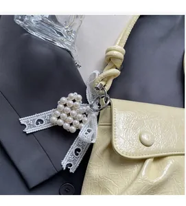 Détail du sac beige plissé avec pendentif perle cœur et ruban en dentelle sophistiqué