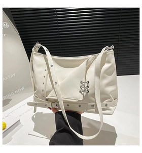 Detailed view of cream PU shoulder bag featuring punk silver metal eyelets and ring hardware