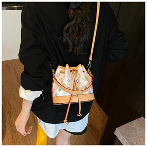 Detail shot of a mini bucket bag with colorful monogram prints and leather trim on a model