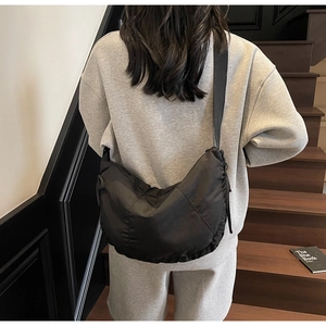 Close-up of black nylon crescent bag worn by a model in a minimalist urban setting