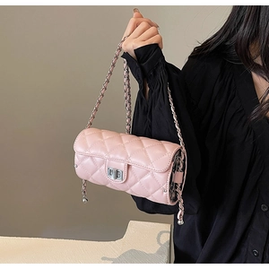 Detail of pink quilted cylindrical bag featuring silver twist lock and woven chain strap