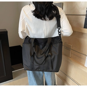 Rear view of a model wearing the black waterproof nylon tote bag with wide strap
