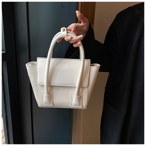 Detailed view of a cream PU leather handbag with gold metal buckles and twin top handles