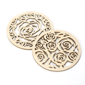 Detail of laser-cut wooden coasters with intricate rose flower hollow patterns