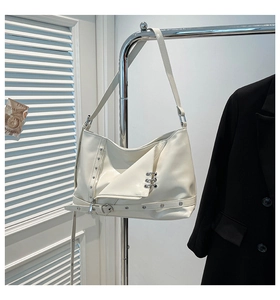 Detail of off-white faux leather crossbody bag with silver punk rings and zipper accents