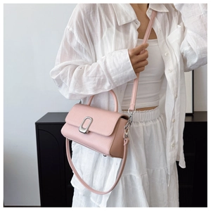 Close-up of pink crossbody bag with litchi grain texture and silver metal buckle