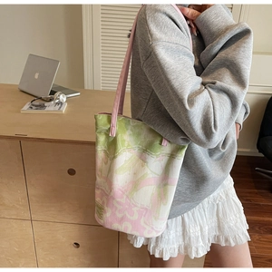 Detailed view of floral canvas bucket bag with pink straps in a modern lifestyle setting
