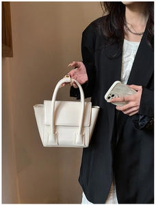 Detailed view of beige PU leather handbag showing trapezoidal shape and side accordion folds