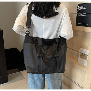 Detail view of large black nylon tote bag with wide detachable strap and side pockets