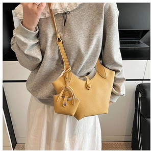 Detail of yellow lychee grain leather bucket bag with matching mini pouch charm and snap closure