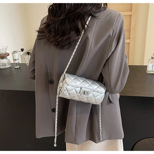 Silver quilted cylindrical crossbody bag with chain strap styled on a model outfit