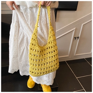 Detail of yellow hollow knit crochet mesh tote bag held by a model in casual style