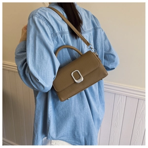 Detailed view of brown lychee grain leather handbag with silver U-shaped metal buckle