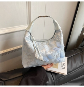 Detailed macro view of light blue lace handbag with 3D butterfly embroidery and silver buckle