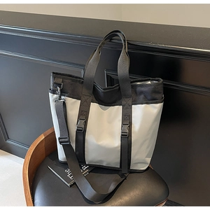 Close-up of color-block tote bag with buckle straps and adjustable shoulder strap