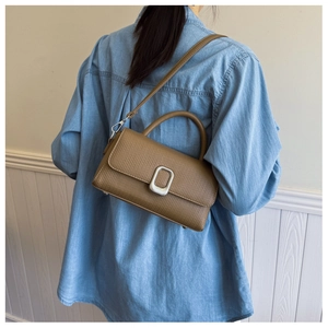 Detailed back view of a brown pebbled leather satchel on a model in a denim shirt