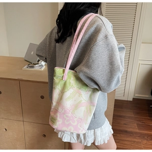 Detailed view of canvas tote bag with pink and green floral print on a side-worn model