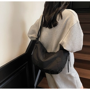 Detail of a black nylon crescent bag featuring a drawstring side and adjustable strap