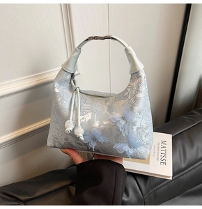 Détail du sac à main bleu clair avec broderie florale et papillons en maille 3D