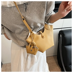 Detail view of yellow leather bucket bag featuring a matching mini pouch and magnetic closure