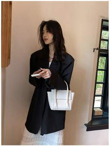Detail of white PU leather square handbag paired with a minimalist black blazer jacket