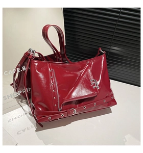 Detail of burgundy biker jacket style handbag with silver zippers and metal rivets
