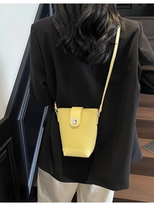 Minimalist yellow leather bucket bag with silver metal buckle closure and shoulder strap
