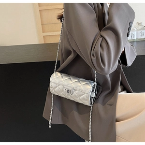 Detail of silver quilted cylinder bag featuring a metallic finish and chain strap