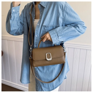 Brown rectangular crossbody bag with silver buckle and woven texture on denim outfit