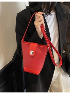 Minimalist red leather bucket bag with silver lock and adjustable strap on a model