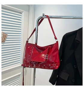Detail of red punk shoulder bag featuring metallic rings, zipper decor and buckled strap