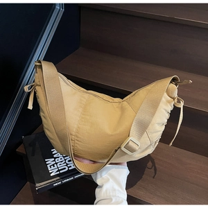 Detail of beige crescent shoulder bag with adjustable strap and drawstring side ruching
