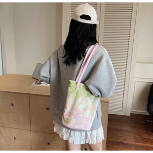 Lifestyle view of a floral jacquard bucket bag with pink straps worn by a model