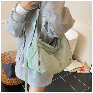 Detailed shot of large light green nylon crossbody bag showing strap and side logo label