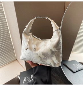 Détail du sac demi-lune blanc avec broderie dentelle, papillons 3D et poignée en argent