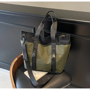 Detailed view of olive green and black nylon tote bag with plastic buckles on a chair